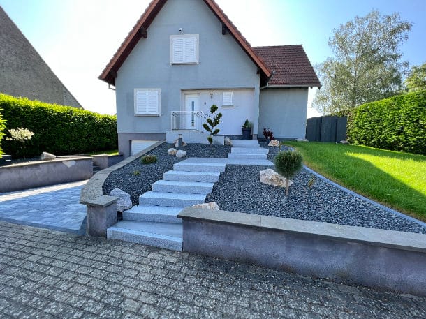 2023-Paillage minéral – jardin minimaliste Une maison avec un paillage minéral en Alsace, où il n'y a pas de plantations. Le jardin de devant n'a aucune valeur écologique et est loin d'être durable. De même, la petite prairie à droite ne présente aucun avantage écologique pour l'environnement.